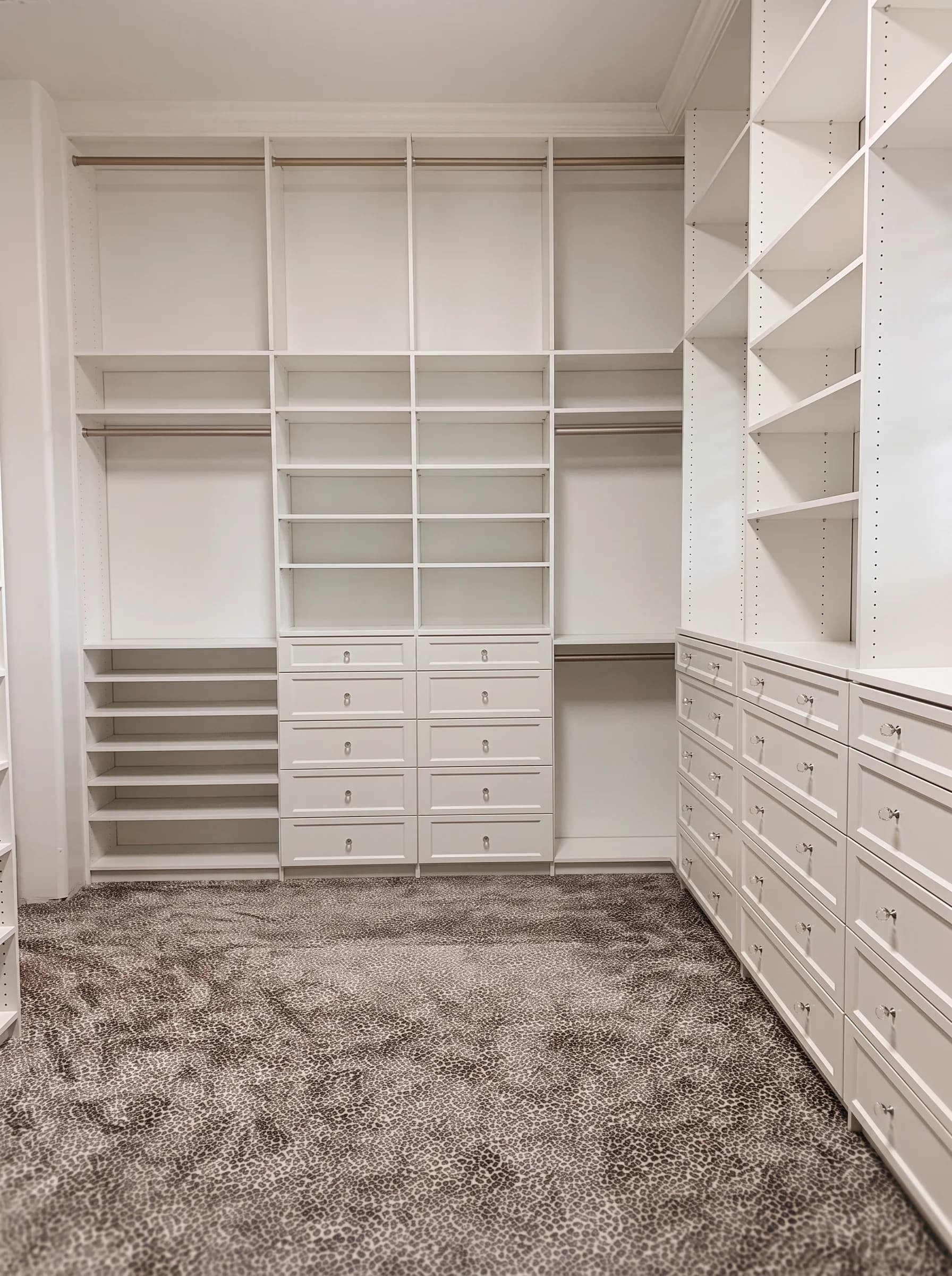 White walk-in closet wall unit with cubbies, drawers, and double hanging