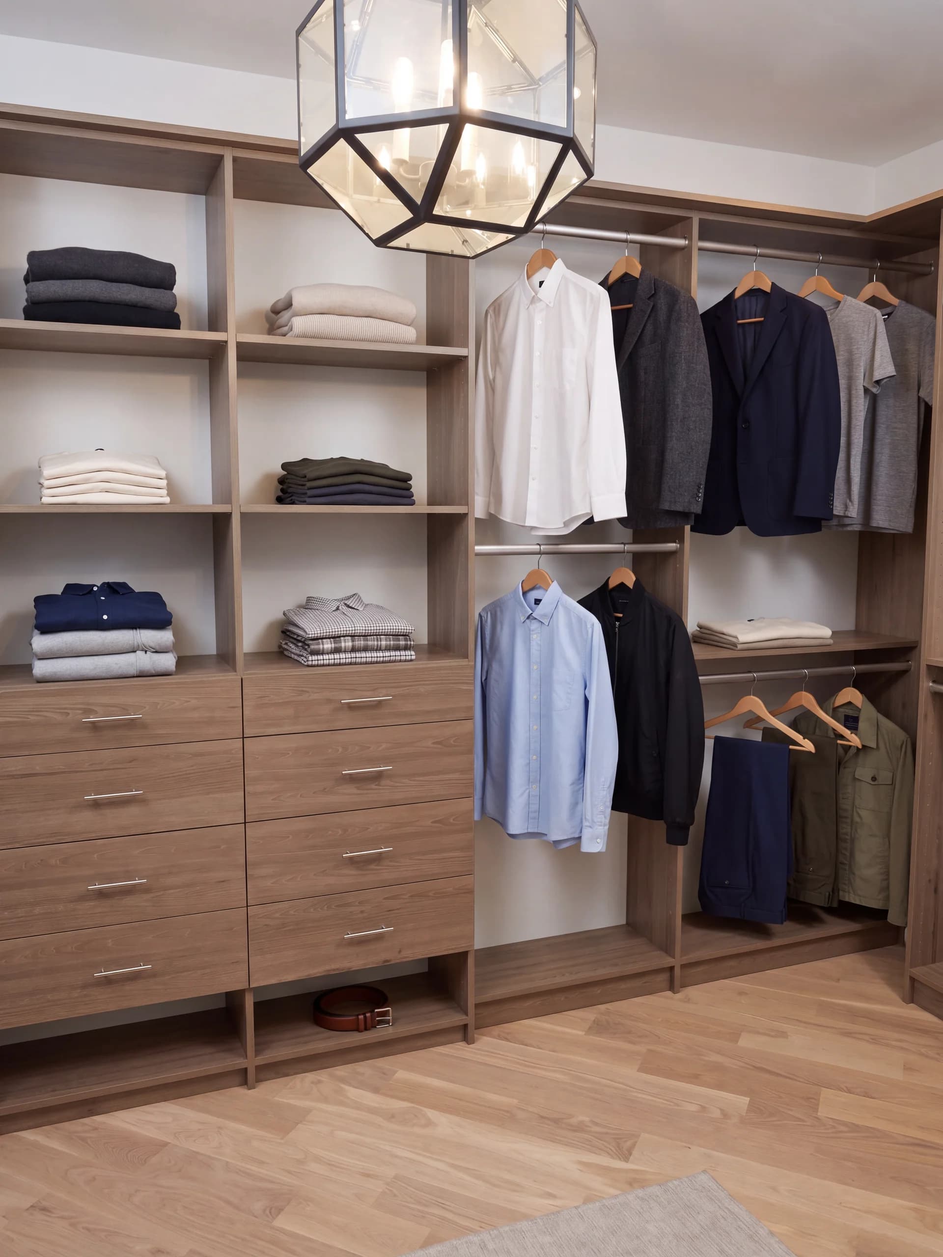 Two-tone walk-in closet in woodgrain and white with a lantern pendant light and folded knitwear on open shelves