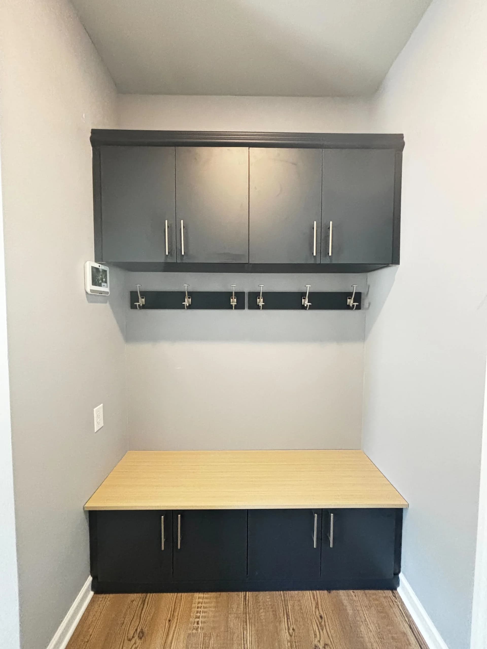 Custom mudroom built-in with navy cabinets, a maple bench, and a coat hook rail