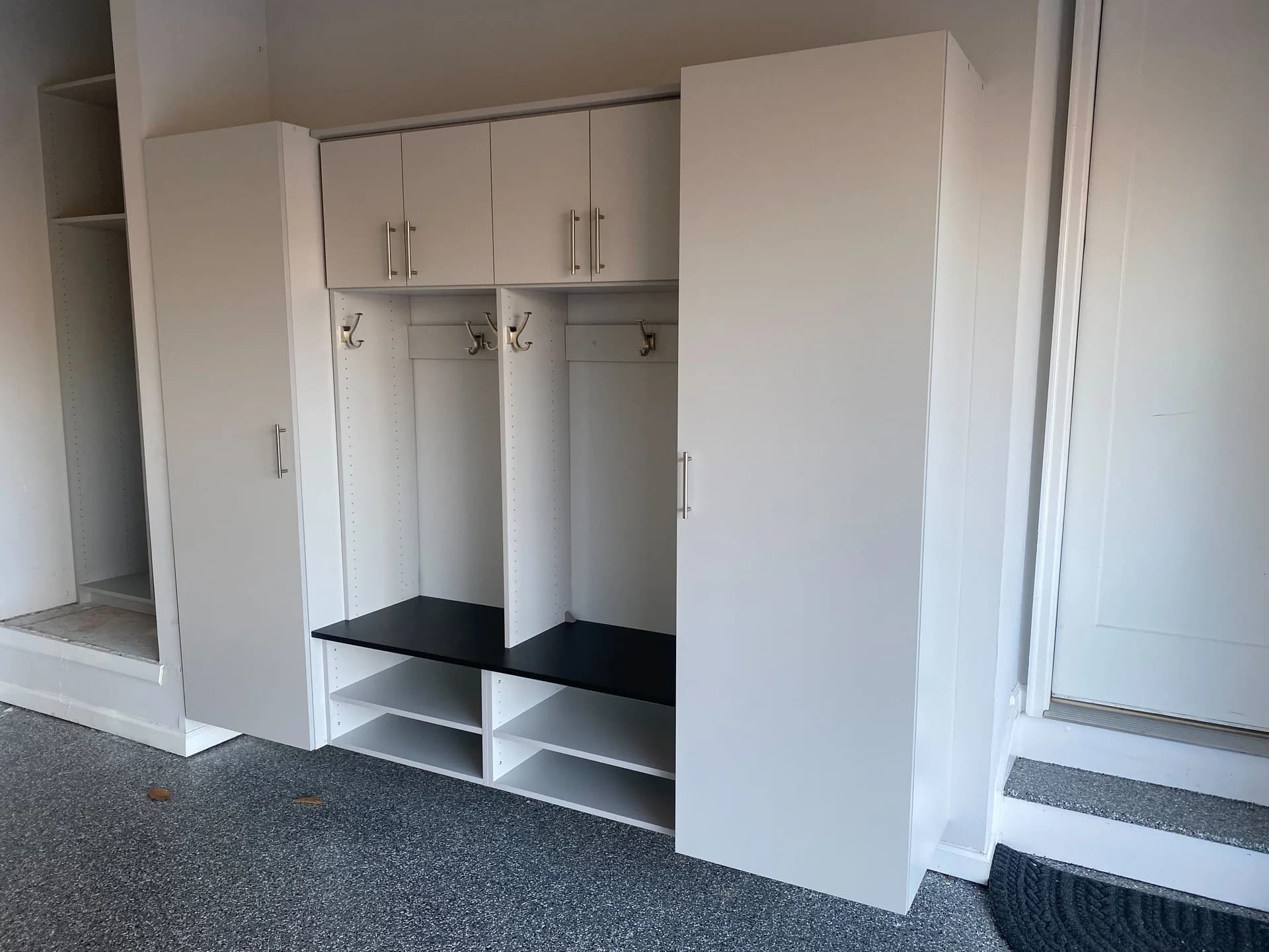 White mudroom lockers with a black bench seat and open cubbies